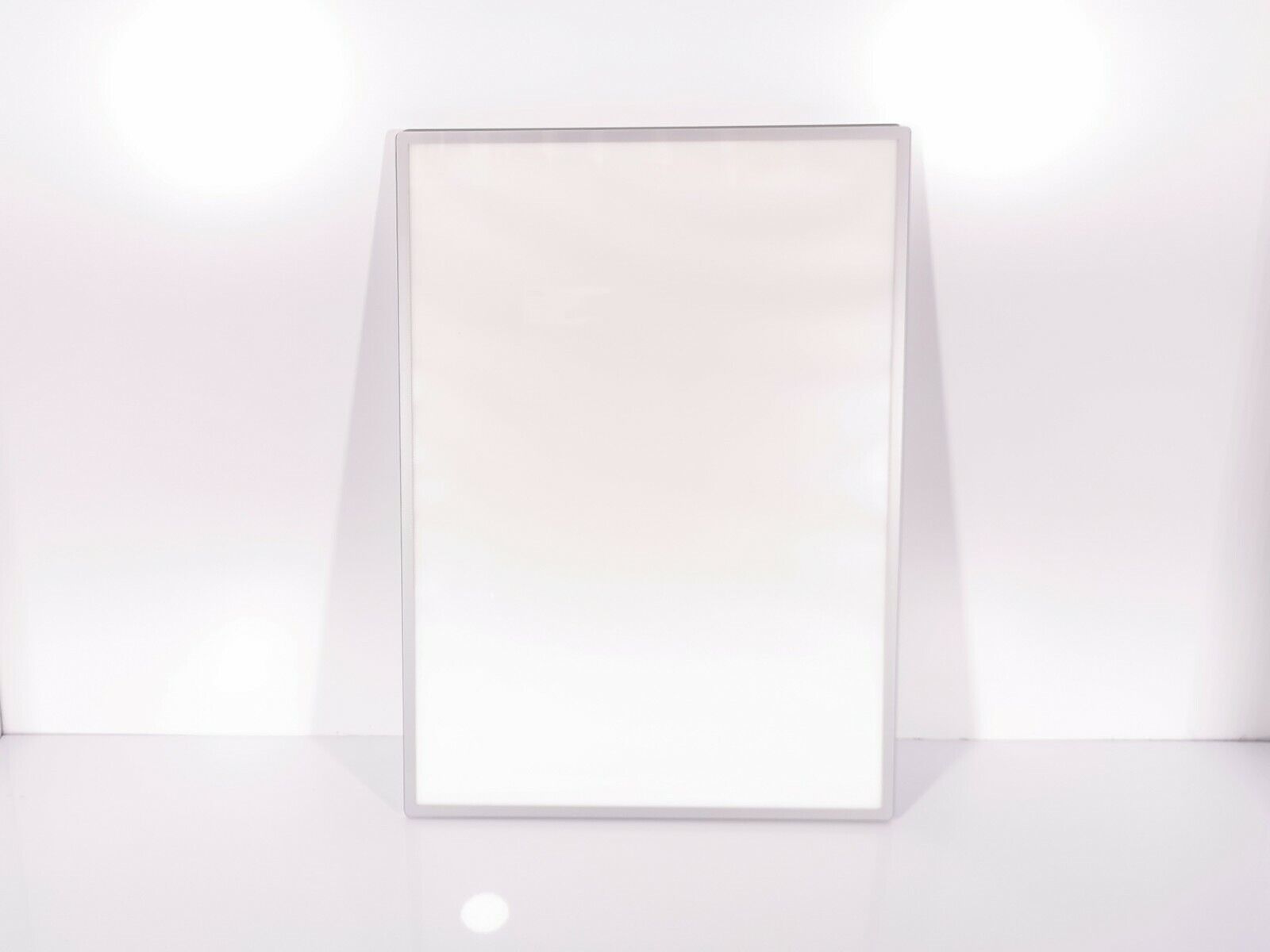 A sleek and minimalist LED Light Box A2 Silver Slim Advertising Wall Mounted Display from Eledtric stands upright against a smooth, bright background, creating a clean and modern look.